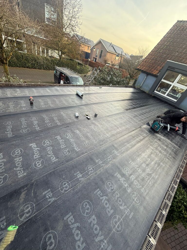 Wortelwerende bitumen dakbedekking aangebracht op een plat dak tijdens een dakrenovatie in Amersfoort.